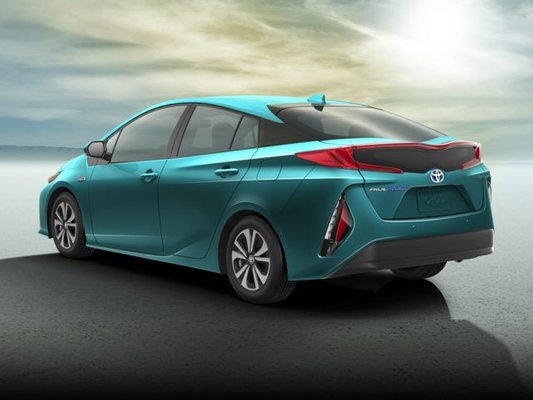 Image of a teal 2019 Toyota Prius Prime parked in front of a sunset.